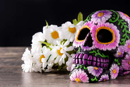 Typical Mexican skull and flowers diadem on wooden table. Day of the Dead.