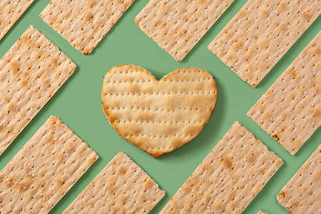 Traditional matzah bread pattern and heart shaped matzah on green backgroundの写真素材