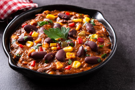 Traditional mexican tex mex chili con carne in iron pan on black stone backgroundの写真素材