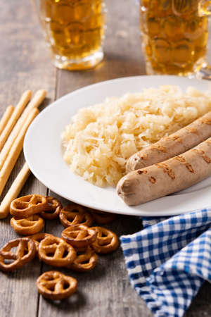 Bratwurst sausage, sauerkraut, pretzels and beer on wooden tableの写真素材