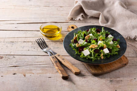 Beetroot salad with feta cheese, lettuce and walnuts on wooden tableの写真素材