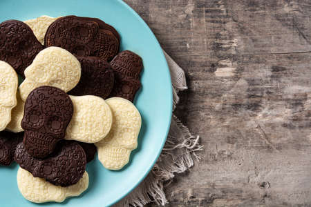 Chocolate Mexican skulls in plate on wooden tableの写真素材