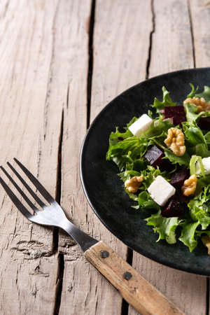 Beetroot salad with feta cheese, lettuce and walnuts on rustic wooden table