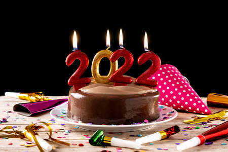2022 cake and ornaments on wooden table and black background
