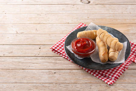 Latin American tequeÃ±os stuffed with cheese on wooden table