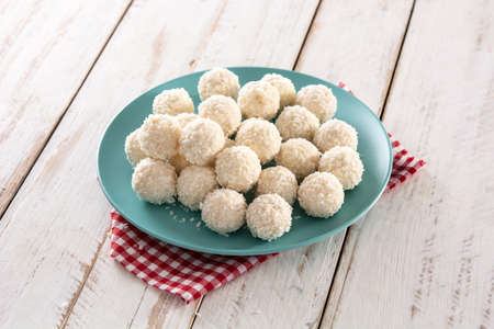 Homemade coconut balls on white wooden table