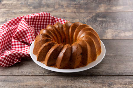 Traditional bundt cake piece with raisins on wooden table