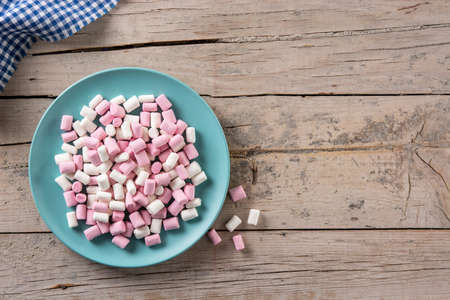 Sweet marshmallows topping in a blue plate on wooden tableの写真素材