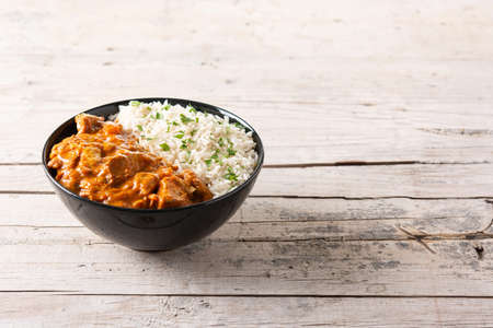 Indian butter chicken in black bowl on wooden tableの写真素材