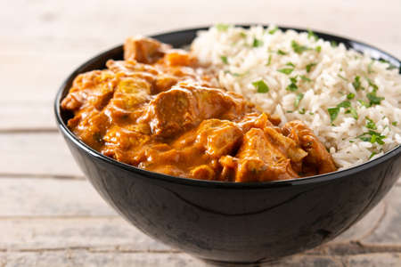 Indian butter chicken in black bowl on wooden tableの写真素材