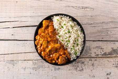 Indian butter chicken in black bowl on wooden tableの写真素材