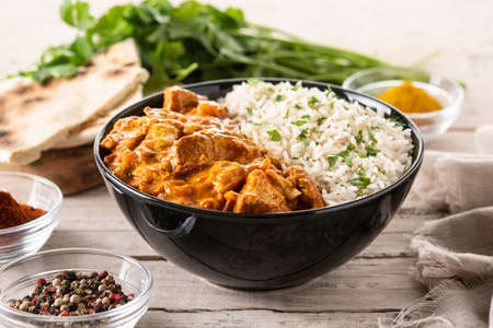 Indian butter chicken in black bowl on wooden tableの写真素材