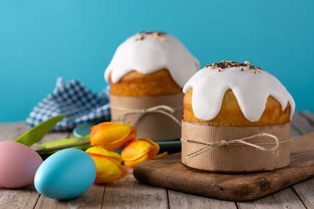 Traditional Easter cake, colorful eggs and tulips on wooden table.
