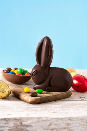 Easter chocolate bunny and colorful eggs on wooden table and blue backgroundの写真素材