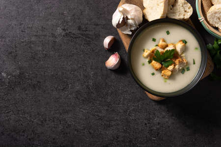 Garlic soup topped with croutons in bowl on black slate backgroundの写真素材