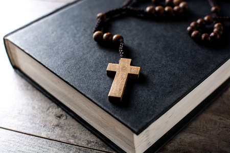 Rosary catholic cross on holyBible on wooden table