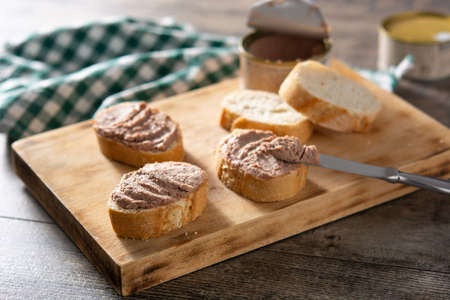 Dipping toasted bread with pork liver pate on wooden table