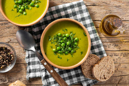 Green pea soup in a bowl on rustic wooden table