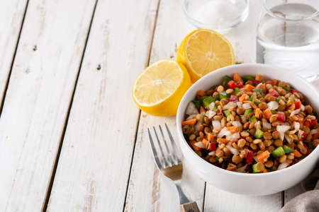 Lentil salad with peppers,onion and carrot in bowl on wooden tableの写真素材