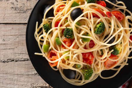 Spaghetti with vegetables(broccoli,tomatoes,peppers) on wooden tableの写真素材