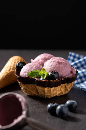 Blueberry ice cream scoops with waffle on black backgroundの写真素材