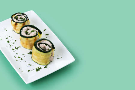Grilled zucchini rolls with tuna and cream cheese on green backgroundの写真素材