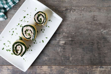 Grilled zucchini rolls with tuna and cream cheese on wooden table