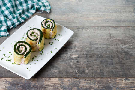 Grilled zucchini rolls with tuna and cream cheese on wooden table. copy-spaceの写真素材