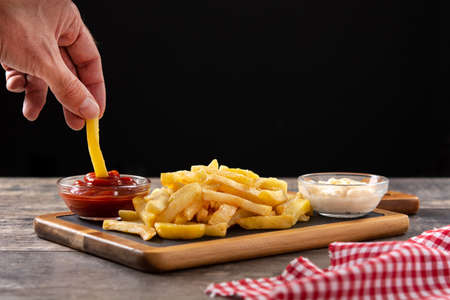 Fried potatoes with ketchup and mayonnaise on wooden tableの写真素材