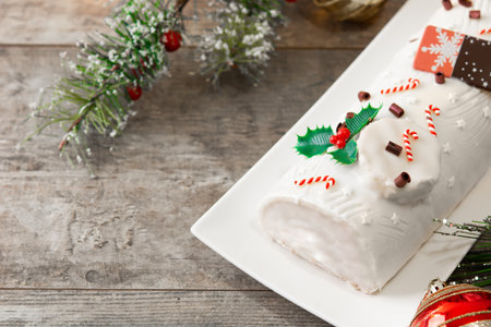 White chocolate yule log cake with christmas ornament on wooden table. copy-spaceの写真素材