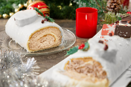 White chocolate yule log cake with christmas lights on wooden tableの写真素材
