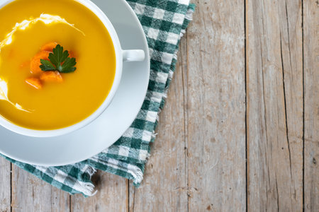 Carrot soup with cream and parsley on wooden table.の写真素材