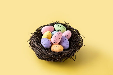 Colorful Easter eggs inside a nest on yellow background