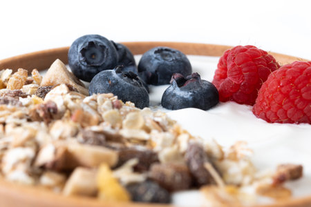 Yogurt with berries and muesli for breakfast in bowl isolated on white backgroundの写真素材