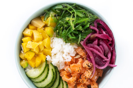 Poke bowl with rice, salmon, cucumber, mango, onion, wakame salad, poppy seeds and sunflower seeds isolated on white backgroundの写真素材