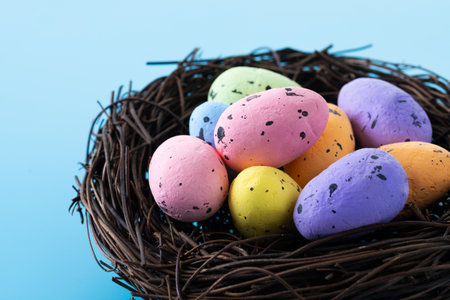 Colorful Easter eggs inside a nest on blue backgroundの写真素材