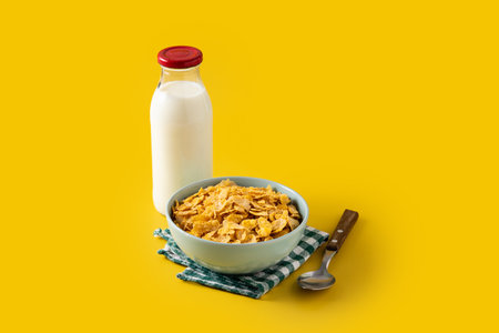 Bowl with cereals and milk bottle for breakfast on yellow backgroundの写真素材