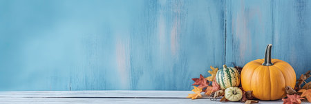 Pumpkin with autumn leaf on blue wooden table with copy space for textの素材
