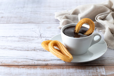 Traditional Spanish churros with hot chocolate breakfast on wooden tableの写真素材