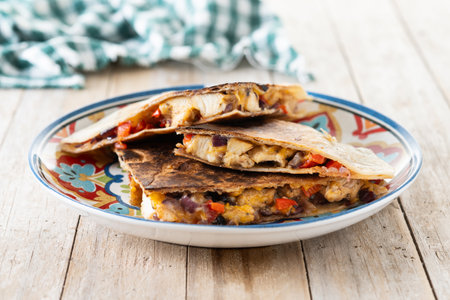 Mexican chicken quesadillas with cheese and peppers on wooden tableの写真素材