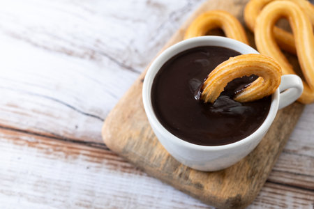 Traditional Spanish churros with hot chocolate breakfast on wooden table. Copy spaceの写真素材