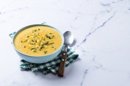 Corn soup in green bowl on white marbleの写真素材