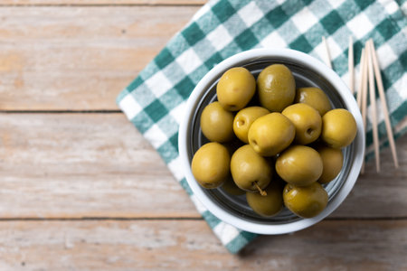 Green olives in a bowl on wooden tableの写真素材