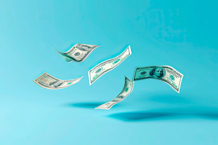 dollar bills falling on blue background. Copy spaceの素材