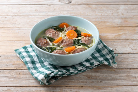 Italian Wedding Soup with meatballs and spinach on wooden tableの写真素材