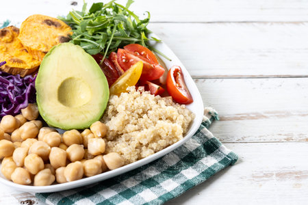 Healthy salad with avocado, lettuce, tomato and chickpeas on wooden tableの写真素材