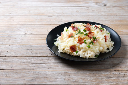 Slovak potato dumplings halusky with steamed sauerkraut and bacon on wooden tableの写真素材