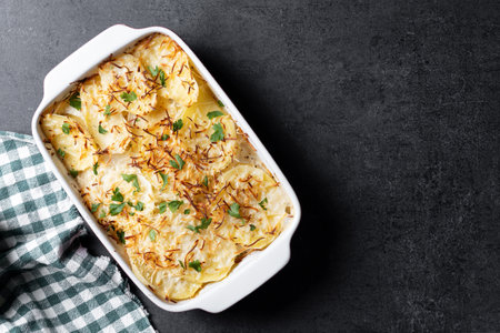 Potato gratin baked with cream and cheese on black slate backgroundの写真素材