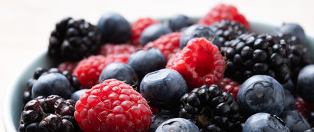 Fresh assortment berries in bowl on wooden table