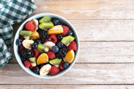 Fruit salad in a blue bowl on wooden tableの写真素材